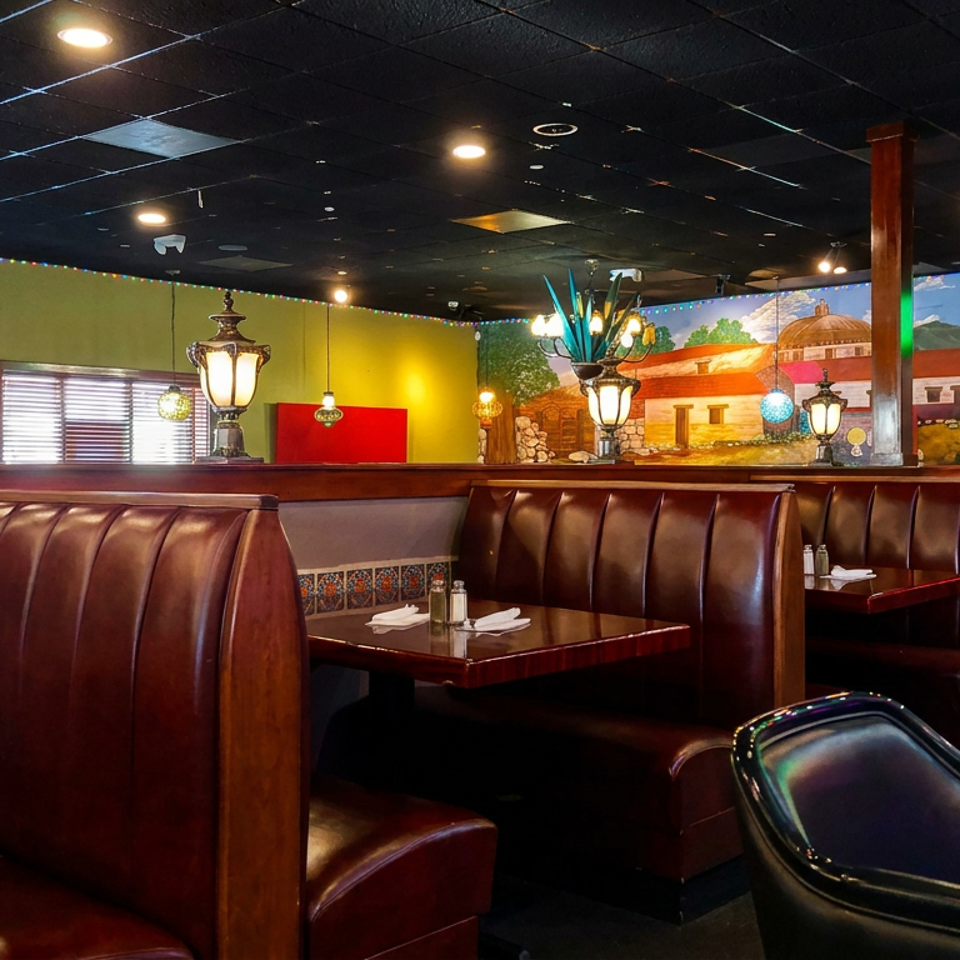 Colorful Mexican-style restaurant dining room with leather booths, polished tables, pendant lamps, and vibrant wall murals.